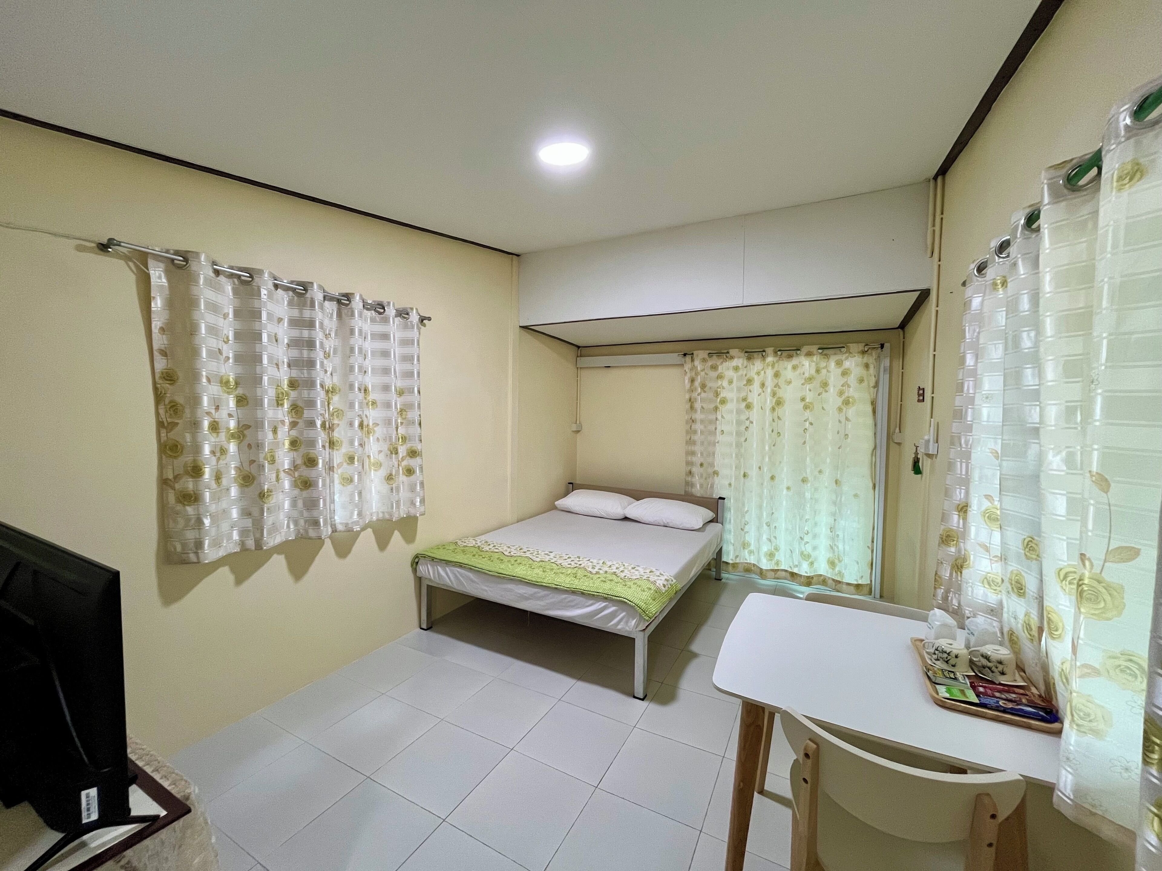 A bedroom with a bed, a desk, and a chair.