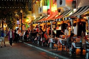 An outdoor dining area with tables and chairs, surrounded by buildings with awnings. - Casagrandesouthbeach by AmericanVacationLiving 4Rm (Miami Beach)