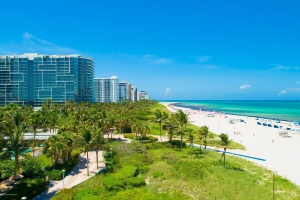 Een strandhotel met zwembad, palmbomen en uitzicht op het strand.