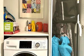 A laundry area with a washing machine, a Scrabble box, and a framed picture on the wall. - Casagrandesouthbeach by AmericanVacationLiving 4Rm (Miami Beach)