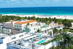 Un hôtel doté d’une piscine sur le toit, offrant une vue sur la plage et bordé de palmiers.