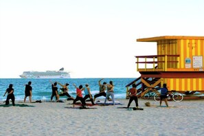 A beach with people exercising, a lifeguard tower, and a cruise ship in the distance. - Casagrandesouthbeach by AmericanVacationLiving 4Rm (Miami Beach)