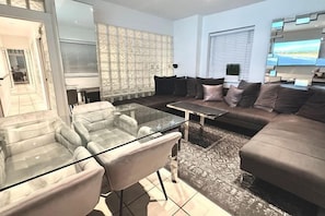 A modern living room with a glass coffee table, leather sofas, and a patterned rug. - Casagrandesouthbeach by AmericanVacationLiving 4Rm (Miami Beach)