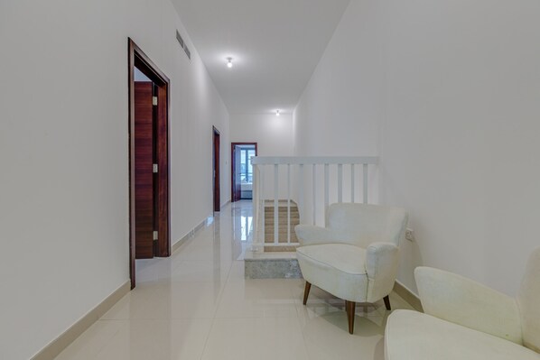 A hallway with a white chair, a wooden door, and a staircase.