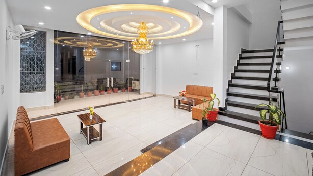 Eine moderne Lobby mit einer Couch, einem Couchtisch, einer Kandelaber, einer Treppe und Topfpflanzen.