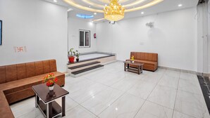 Ein moderner Empfangsbereich mit einer Chandelier, Sofas, einem Couchtisch und einer Treppe, die zu einem Balkon führt.