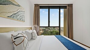 A hotel room with a large bed, a view of the city, and a painting on the wall. - Oswin by Kozystay - Cilandak (Jakarta)