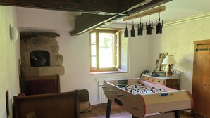 Una habitación acogedora con mesa de futbolín, chimenea y ventana con luces colgantes.