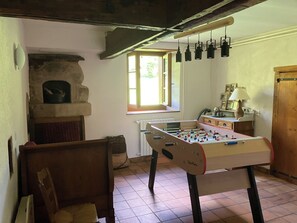 A cozy room with a foosball table, a fireplace, and a window with hanging lights.