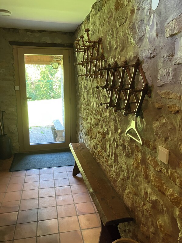 Una stanza con pareti in pietra, una panca e un appendiabiti.