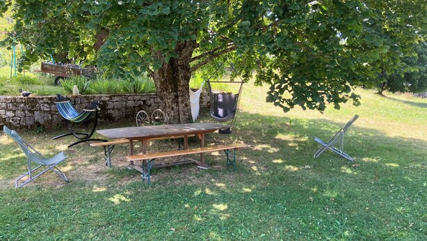 Un montaje para picnic con una mesa de madera, bancos y una hamaca bajo un árbol.