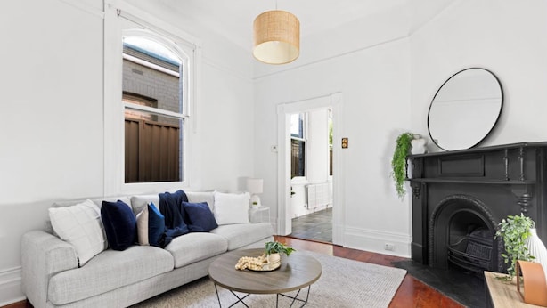 A living room with a grey sofa, a round coffee table, a fireplace, and a large mirror on the wall. - Prime home near train, trams, cafes, schools, Yarra River & city attractions (Richmond)
