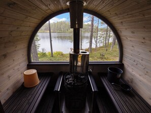 Interior acollidor d'una cabana amb un foc de llenya, una finestra gran amb vista a un llac i un interior de fusta rústic.