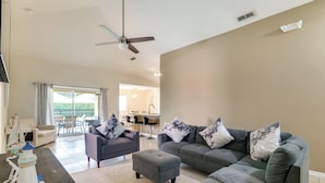 A living room with two grey sofas, a small ottoman, a table with a decorative item, and a ceiling fan. - Peaceful Clermont Gem w/ Pool, 9 Mi to Disney! (Clermont)