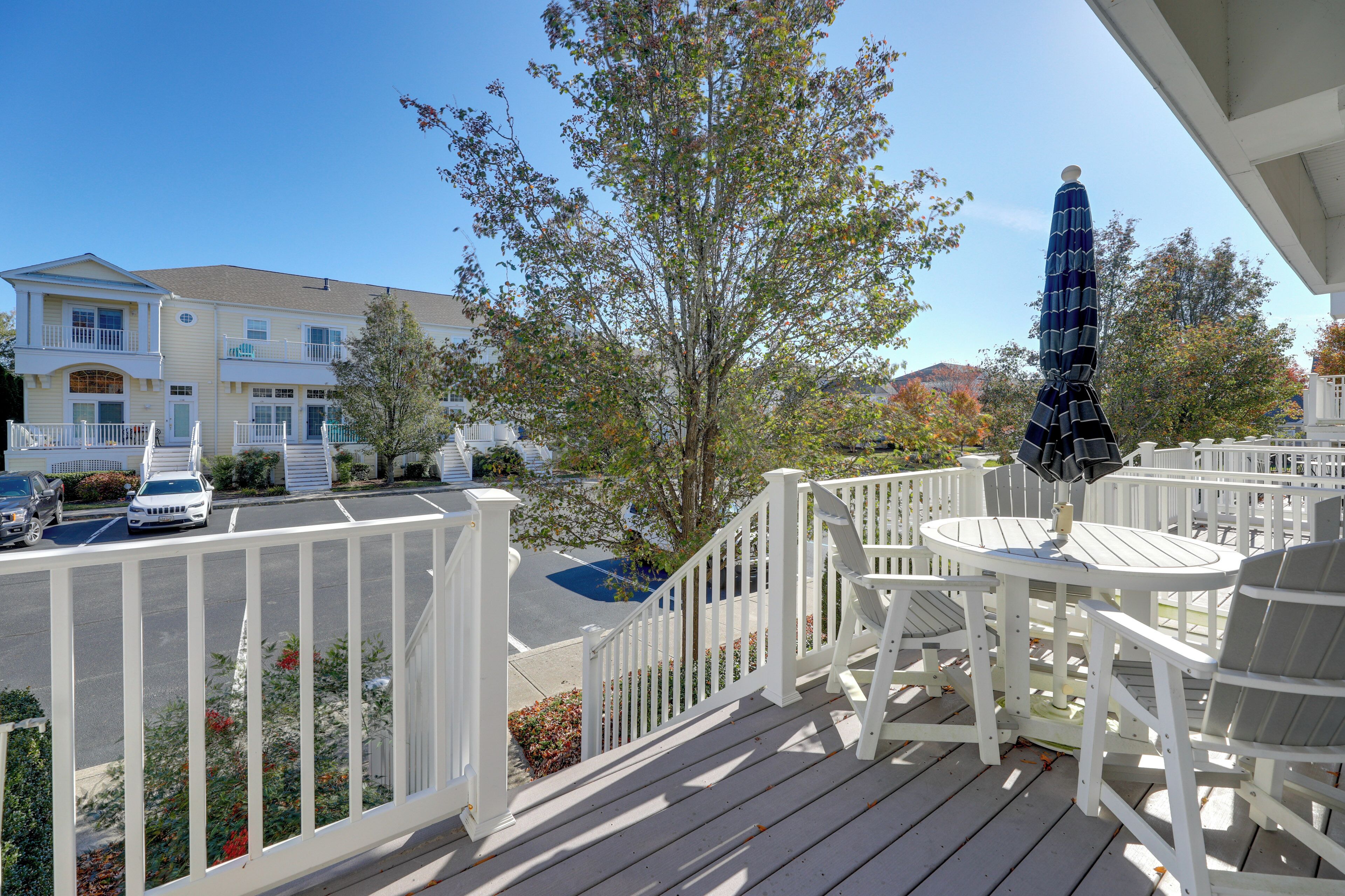 A wooden deck with white railings, a round table, and two chairs.