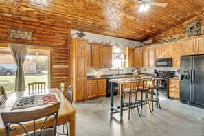 Une cuisine de style rustique, aménagée comme un chalet, avec des meubles en bois, une table à manger et des tabourets de bar.