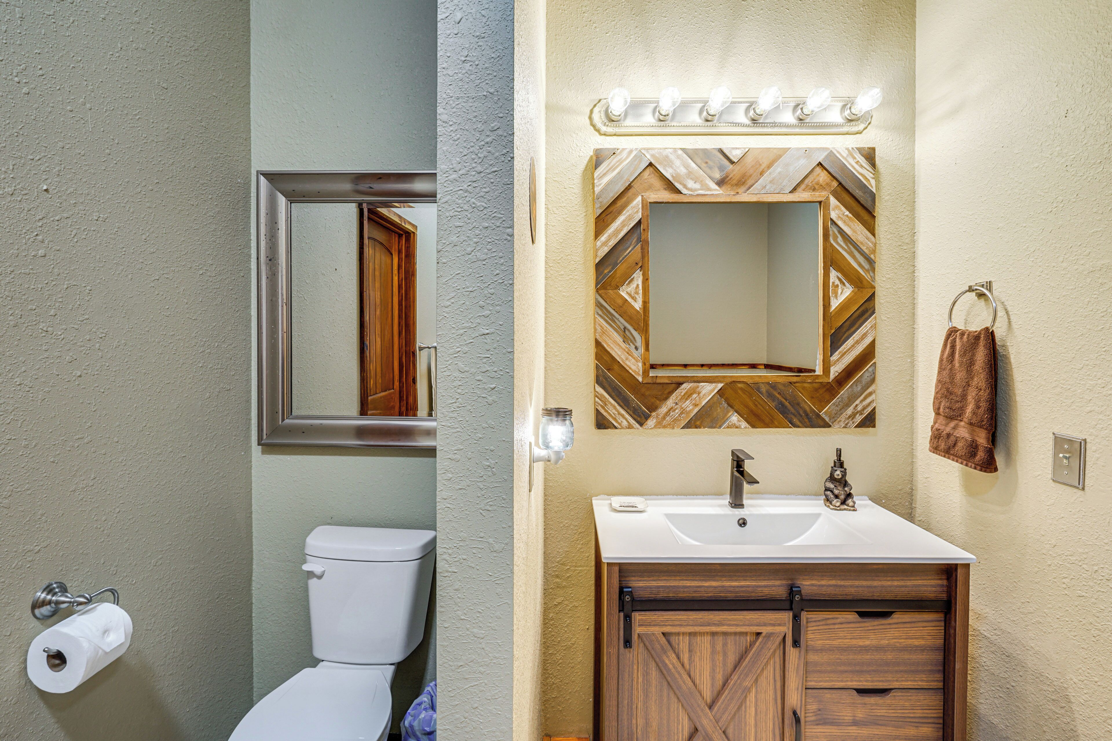 Een badkamer met toilet, wastafel en spiegel.