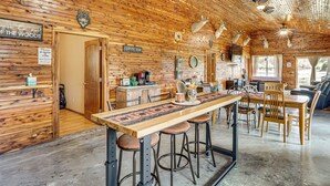 Un intérieur rustique en bois, avec un long bar, des tabourets et un espace repas.