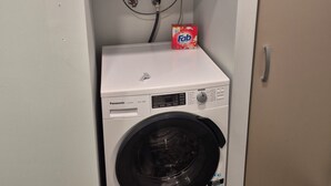 Un appareil compact combinant lave-linge et sèche-linge, doté d’un panneau de commande, d’une étiquette indiquant la consommation d’eau et d’un compartiment à lessive.