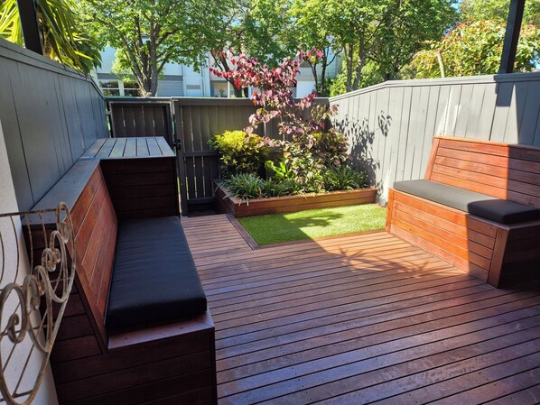 En træterrasse med integreret siddeplads og et lille haveområde.