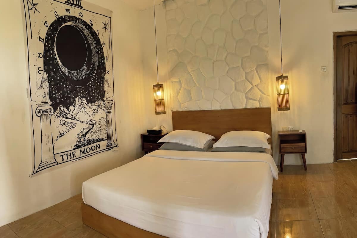 A bedroom with a large bed, two bedside tables, a wall-mounted lamp, and a poster of 'The Moon'.