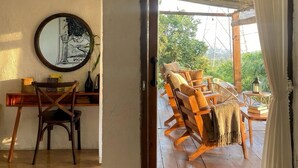 Une pièce comprenant un bureau en bois, une chaise, un miroir et donnant sur un espace extérieur aménagé avec du mobilier en bois.