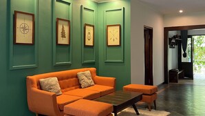 Un salon moderne avec un mur d’accent vert, un canapé d’angle, une table basse et des œuvres d’art encadrées.