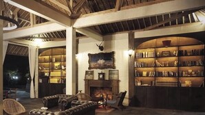 Une salle de lecture chaleureuse, avec des canapés en cuir, une cheminée et des étagères remplies de livres.