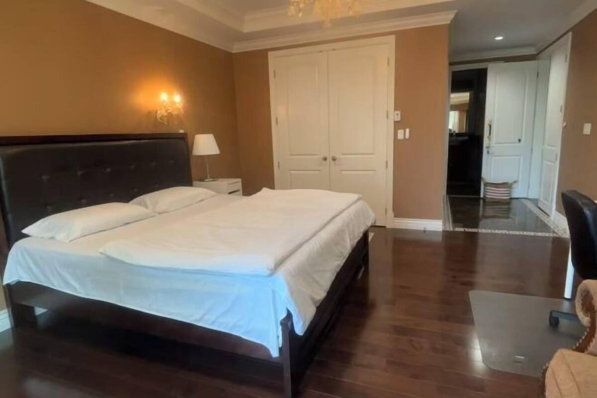 Un dormitorio con una cama grande, una mesita de noche, una lámpara y un armario.