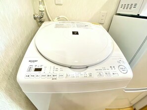 Eine weiße Sharp ES-TX8J Toilette mit Bedienfeld, das verschiedene Tasten und eine digitale Anzeige aufweist.