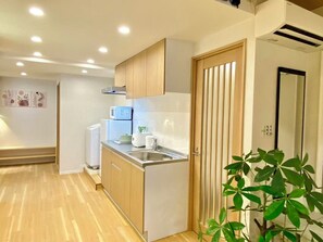 A compact kitchen with wooden cabinets, a built-in microwave, and a sink. - H202 *[New] Luxury Home in Tokyo | Japanese-Style 3LDK | Honjo-Azumabashi Station & Direct Access to the Airport | Near Asakusa & Sky Tree (Sumida-ku)