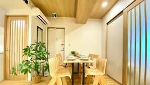 Een eetgedeelte met een houten tafel, stoelen en een potplant.