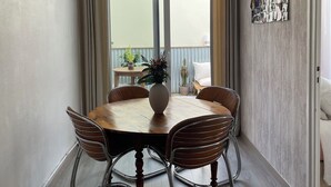 Ruokailutilassa on pyöreä puinen pöytä, neljä tuolia, riippuvalaisin ja seinälle kiinnitetty valokuvakollaasi.