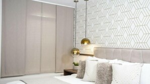 Ein modernes Schlafzimmer mit einem Kopfstück mit geometrischem Muster, einer neutralen Farbgestaltung und einem minimalistischen Design.