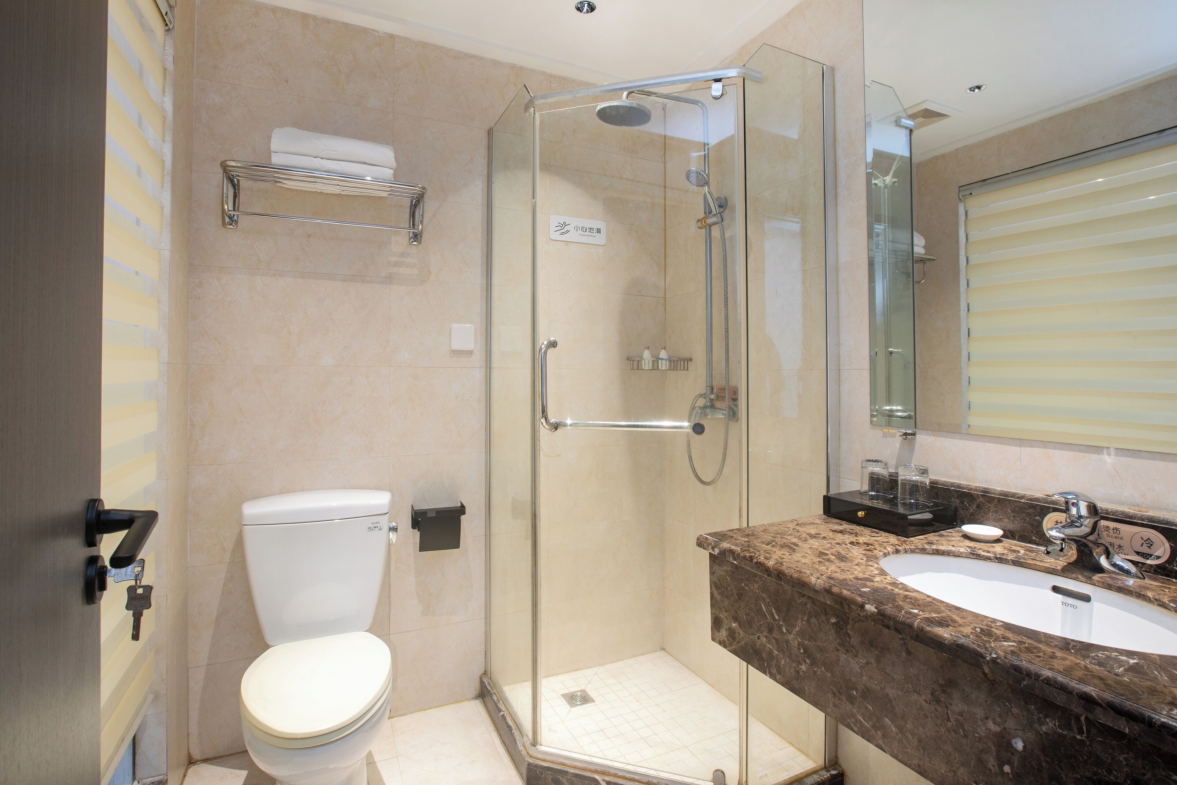 A modern bathroom with a glass-enclosed shower, a toilet, and a marble sink.