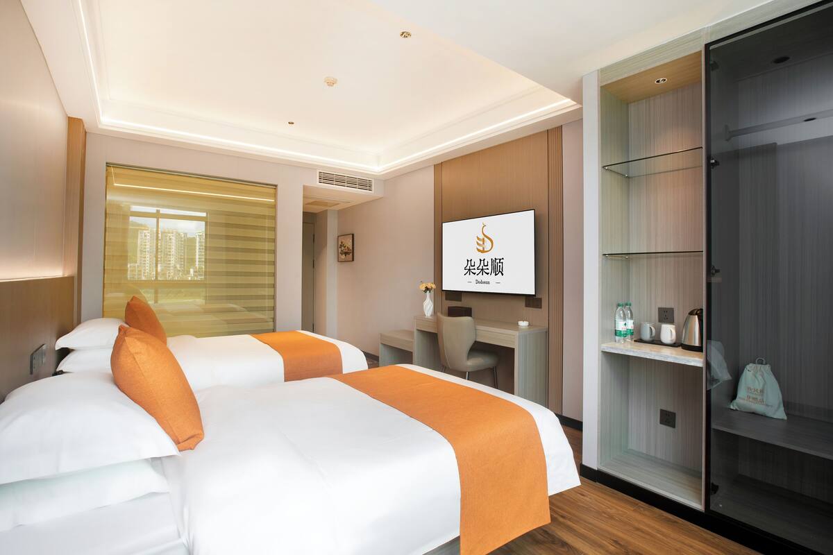 Habitación de hotel con dos camas, un escritorio y un armario.