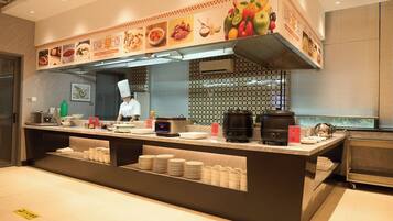 A modern kitchen with a chef preparing food, a digital scale, and a coffee machine.
