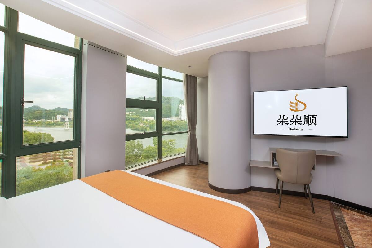Habitación de hotel con una cama grande, un escritorio y un televisor montado en la pared.