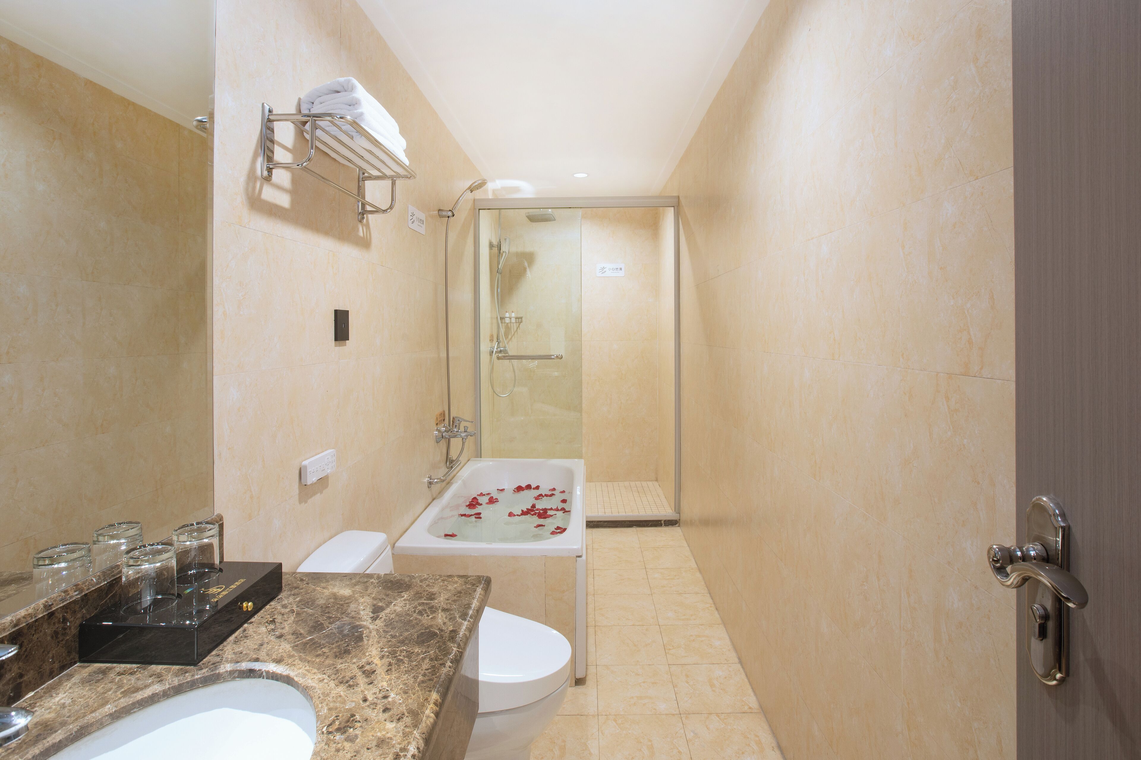 Un baño con lavamanos de mármol, cabina de ducha de vidrio y inodoro blanco.