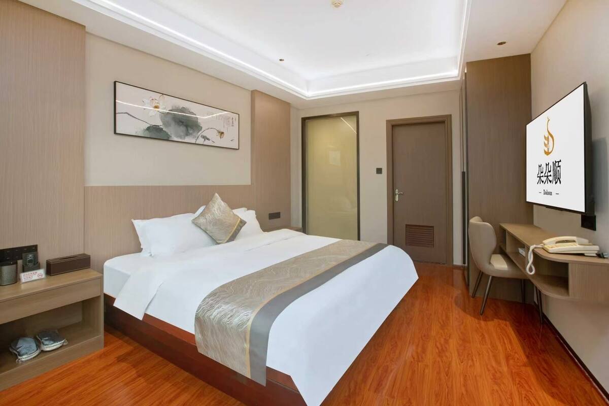 Una habitación de hotel con cama, mesita de noche, silla y escritorio con otra silla.