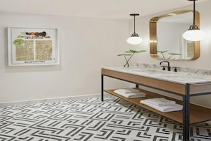 A modern bathroom with a marble sink, a wooden vanity, a large mirror, and a geometric patterned floor. - Kimpton Virgilio Polanco by IHG (Mexico City)