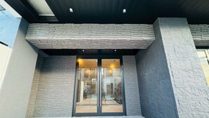 Una entrada de edificio moderna con puerta de vidrio y fachada de piedra.