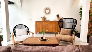 A cozy living room with two black wicker chairs, a wooden coffee table, and a cabinet with decorative items. - Lovely 2BR Villa Close to The Beach (Seminyak)
