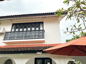 Ein Gebäude mit Balkon, Ziegeldach und Sonnenschirm.