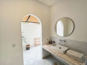 Ein modernes Badezimmer mit freistehender Waschtisch, rundem Spiegel und Handtuchhalter.