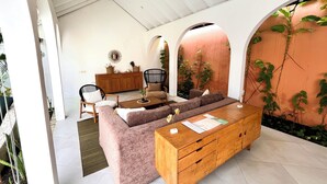 A modern living room with a sofa, wooden coffee table, and a cabinet. There are plants and a mirror on the wall. - Lovely 2BR Villa Close to The Beach (Seminyak)