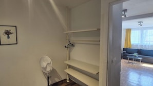 A room with a white fan, a framed picture on the wall, and a doorway leading to a living area with a sofa and a table. - 2BR Apt Next to Vienna Vibrant Center (Vienna)