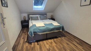 A bedroom with a bed, a nightstand, a bedside table, and a skylight. - 2BR Apt Next to Vienna Vibrant Center (Vienna)