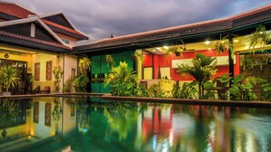 A hotel with a swimming pool, a red building, and lush greenery. - Peaceful 4-Bedroom Villa with Private Pool (Siem Reap)