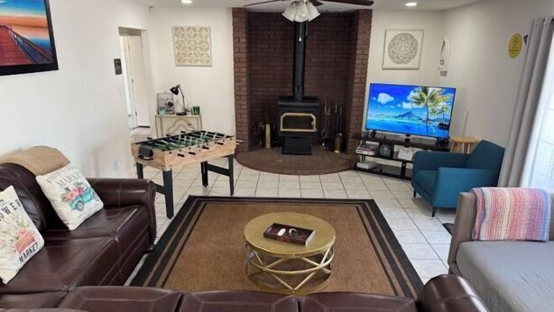 A living room with a fireplace, a television, and a foosball table. - Charming 3-Bedroom Farmhouse Retreat w/ Open Deck! (San Joaquin County)